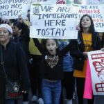 Protesters march holding signs and banners
