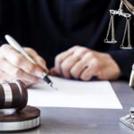 Victims Terrified As Parole Clock Accelerates Judge writing at desk with gavel and Lady Justice statue
