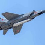 fighter jet with missile flying against a clear blue sky