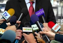 Press microphones surround a suited spokesperson