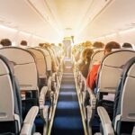 airplane cabin with passengers seated in economy class