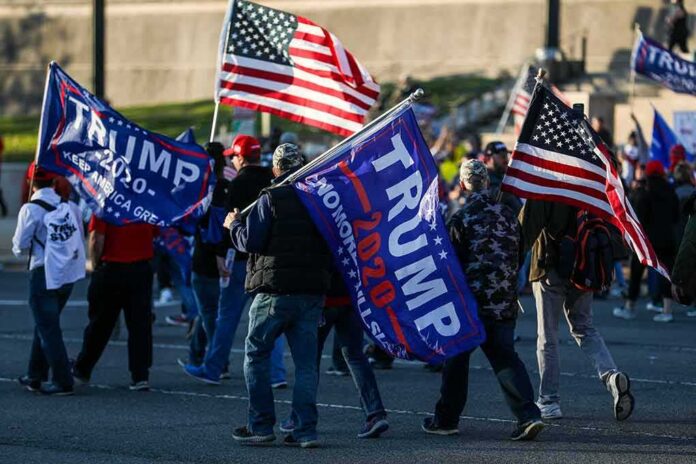 Crowd of people carrying political and American flags at a street gathering