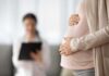 Pregnant woman holding belly during medical visit