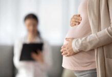Pregnant woman holding belly during medical visit