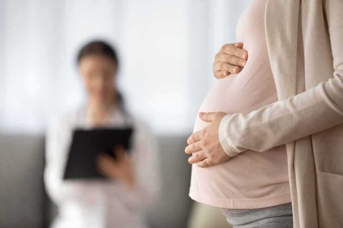 Pregnant woman holding belly during medical visit