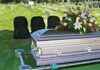 casket with floral arrangement at outdoor graveside service