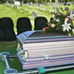 casket with floral arrangement at outdoor graveside service