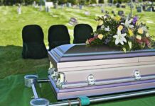casket with floral arrangement at outdoor graveside service
