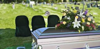 casket with floral arrangement at outdoor graveside service