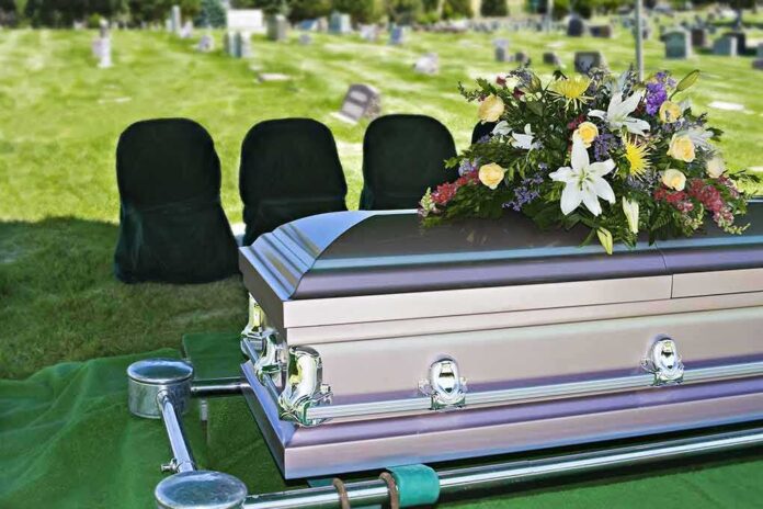 casket with floral arrangement at outdoor graveside service