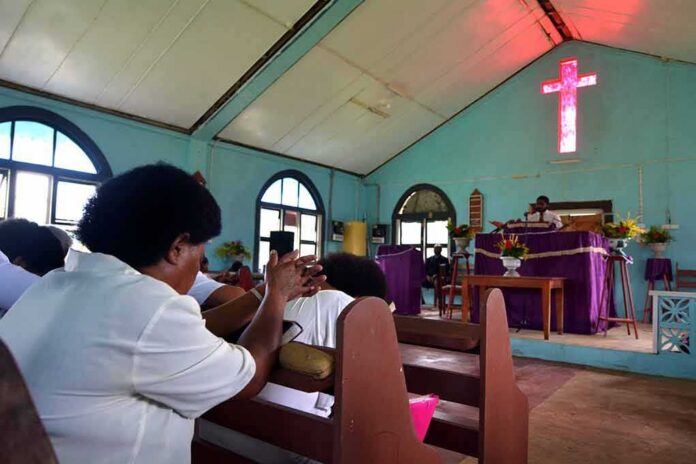 Congregants clapping inside a church with a glowing cross